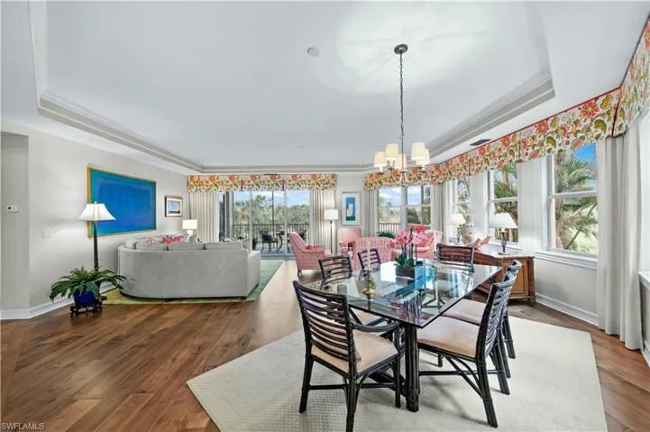 Dining area with wood-type flooring, crown molding, an inviting chandelier, and a tray ceiling