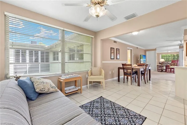 Tiled living room with ceiling fan and ornamental molding