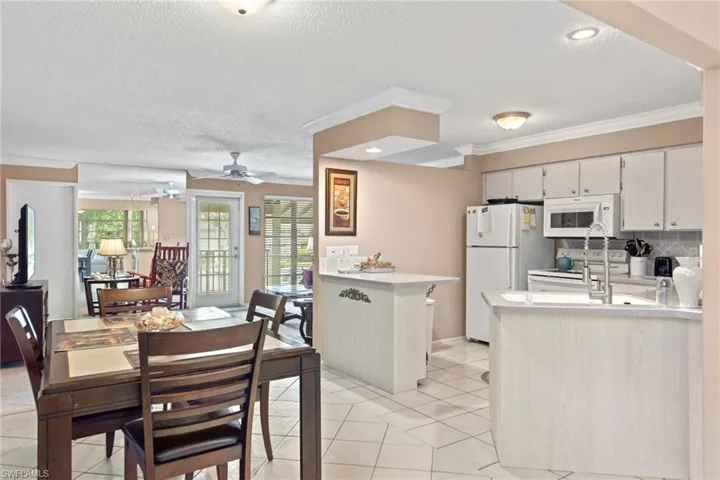 Kitchen with ceiling fan, white appliances, plenty of natural light, and light tile patterned floors