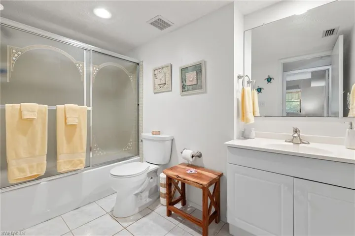 Full bathroom featuring a textured ceiling, toilet, tile patterned floors, vanity, and combined bath / shower with glass door