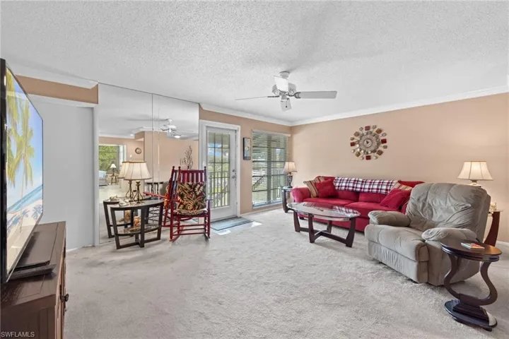 Carpeted living room with a textured ceiling, crown molding, and ceiling fan