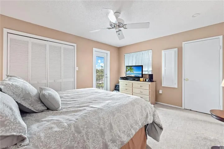Carpeted bedroom featuring ceiling fan, a textured ceiling, and access to outside