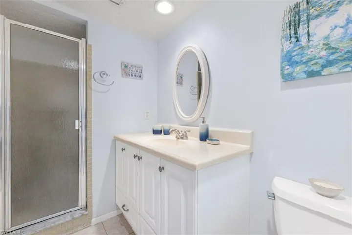 Bathroom with a textured ceiling, toilet, a shower with shower door, tile patterned floors, and vanity