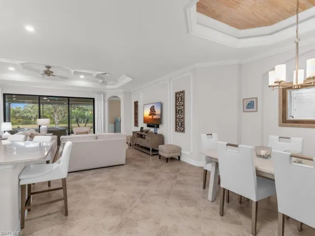 Dining area featuring ceiling fan with notable chandelier, a raised ceiling, wooden ceiling, and crown molding