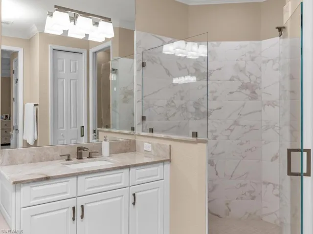 Bathroom with ornamental molding, a shower with door, and vanity