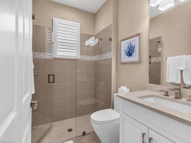 Bathroom with toilet, an enclosed shower, and vanity