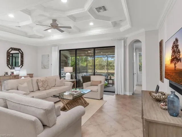 Living room with ornamental molding, ceiling fan, and coffered ceiling