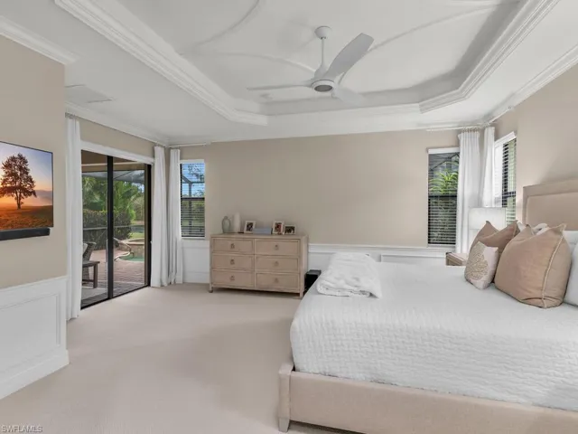 Bedroom with ceiling fan, access to outside, a tray ceiling, and light colored carpet