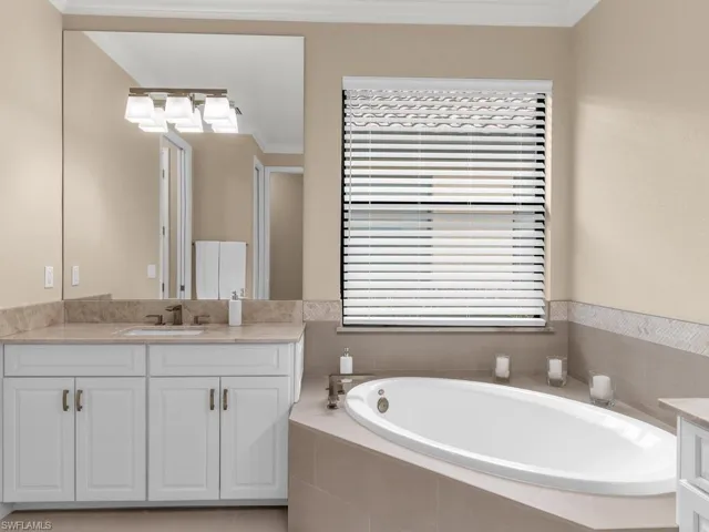 Bathroom featuring ornamental molding, tiled bath, and vanity