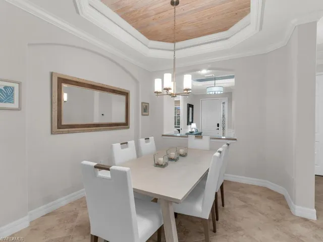 Dining room featuring wood ceiling, an inviting chandelier, crown molding, and a tray ceiling