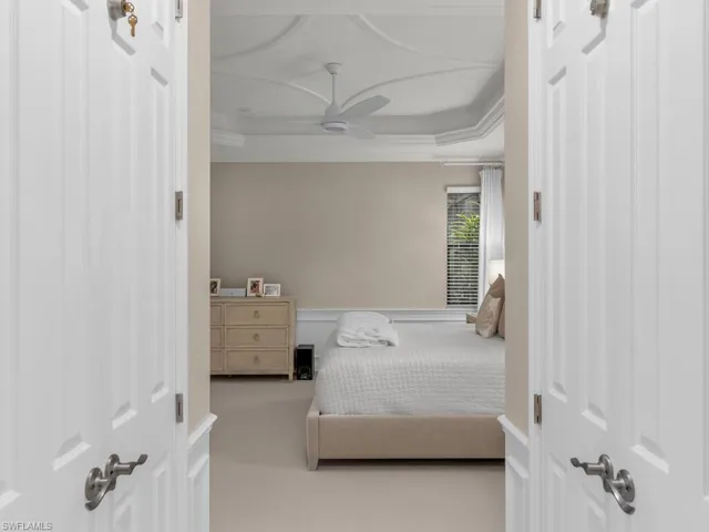 Bedroom with ornamental molding, ceiling fan, a tray ceiling, and carpet flooring