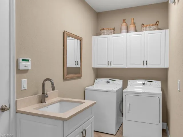 Washroom featuring sink, washing machine and dryer, light tile patterned floors, and cabinets