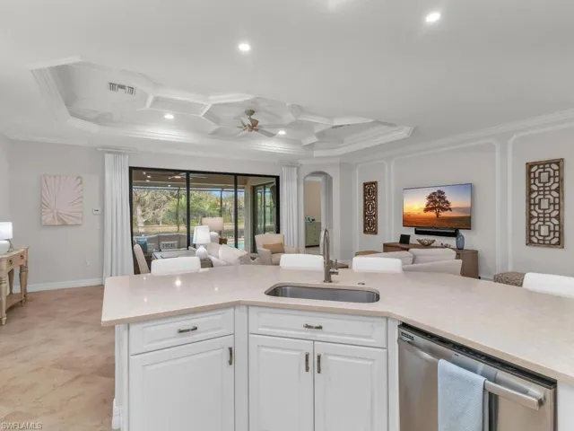 Kitchen featuring stainless steel dishwasher, ceiling fan, white cabinetry, ornamental molding, and sink