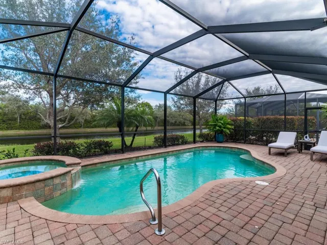 View of pool with glass enclosure, an in ground hot tub, and a patio area