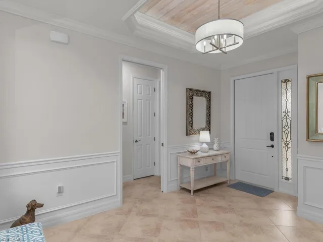 Tiled entrance foyer with a notable chandelier and crown molding