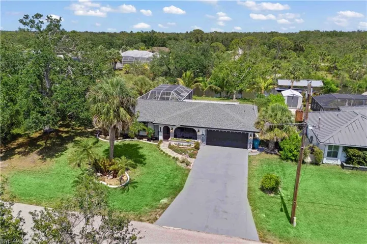 A sweeping aerial shot captures the elegant front entrance and inviting outdoor spaces of the home.