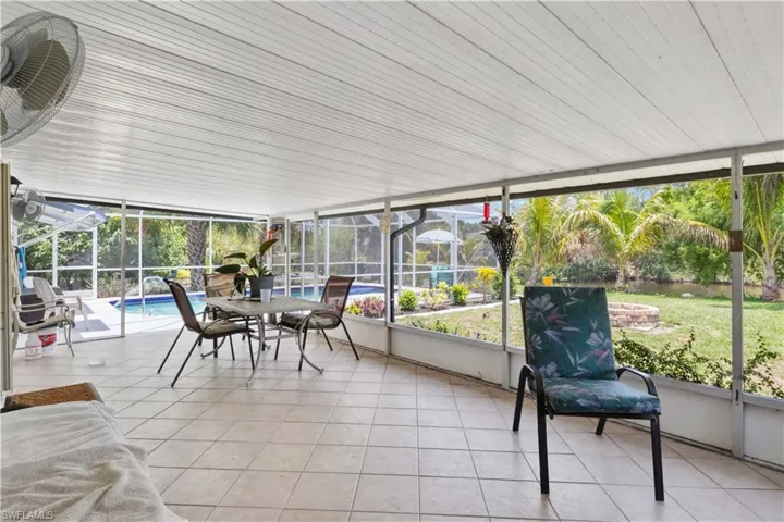 The lanai offers a breezy, shaded spot to relax while enjoying views of the pool, lush gardens, and a cozy firepit perfect for cooler evenings.