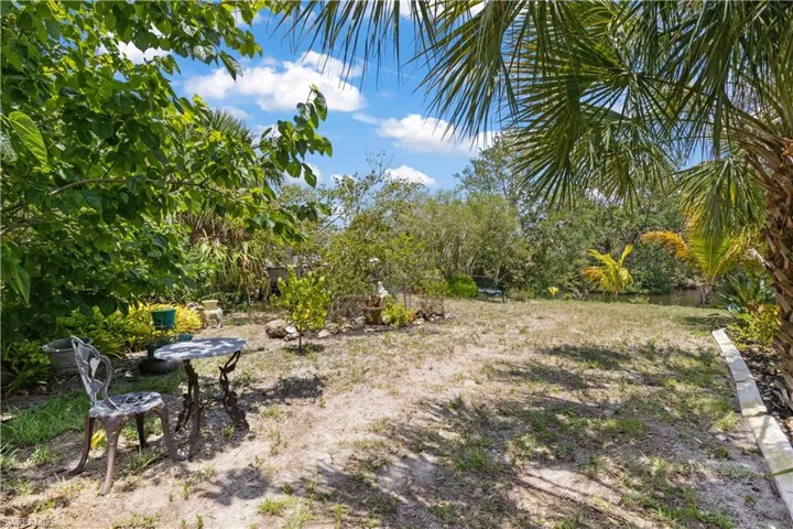 A secluded spot featuring a cozy table is nestled along a winding, hidden pathway surrounded by lush greenery, just steps from the water.
