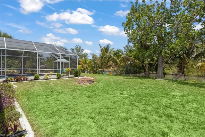 The backyard offers a perfect blend of water views, a welcoming firepit, refreshing pool, and lush green lawn.