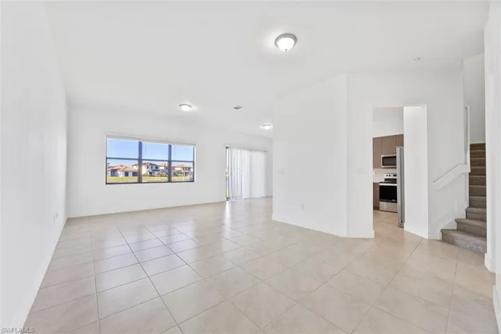 Spare room featuring stairway, baseboards, and light tile patterned flooring