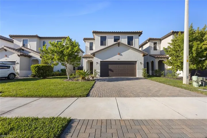Mediterranean / spanish-style home with stucco siding, a tiled roof, decorative driveway, and a front lawn