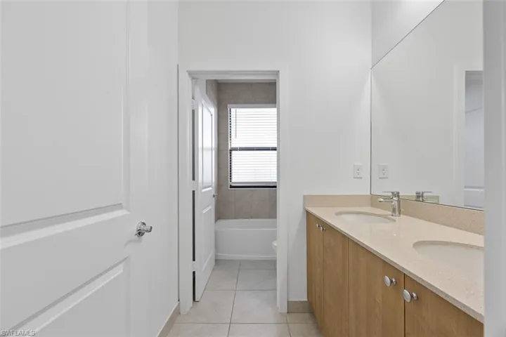 Bathroom with a sink, a bath, double vanity, and tile patterned flooring