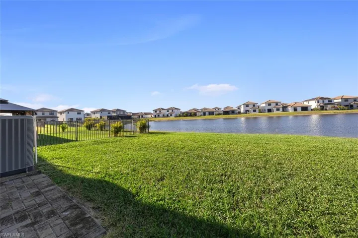 View of yard featuring a residential view, fence, central AC, and a water view