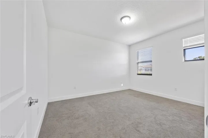 Carpeted empty room with a textured ceiling and baseboards