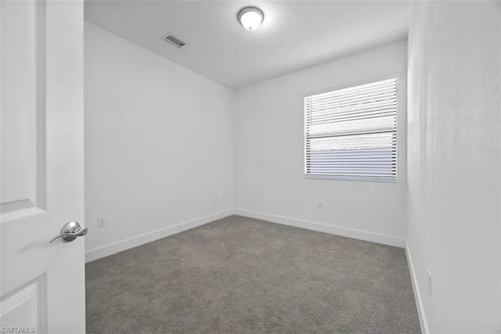 Spare room featuring visible vents, a textured ceiling, baseboards, and carpet