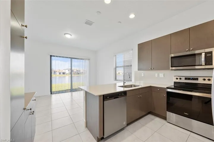 Kitchen with a sink, appliances with stainless steel finishes, a peninsula, light countertops, and light tile patterned floors