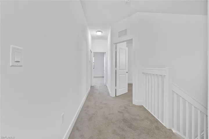 Hall featuring visible vents, an upstairs landing, carpet, and baseboards