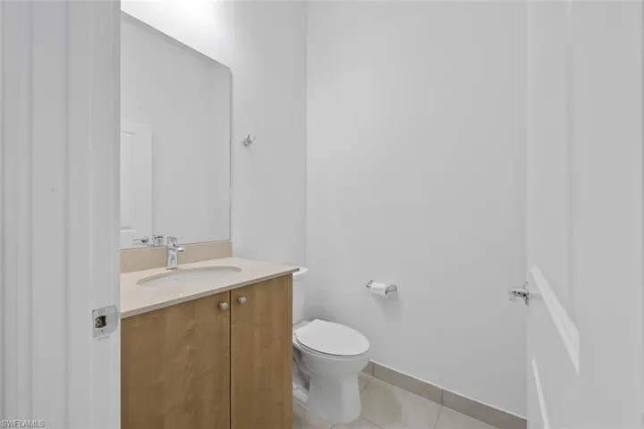 Half bath featuring tile patterned flooring, toilet, vanity, and baseboards