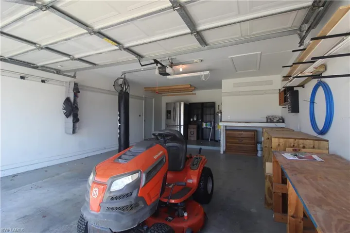 Garage featuring a workshop area, stainless steel fridge, strapped water heater, and a garage door opener