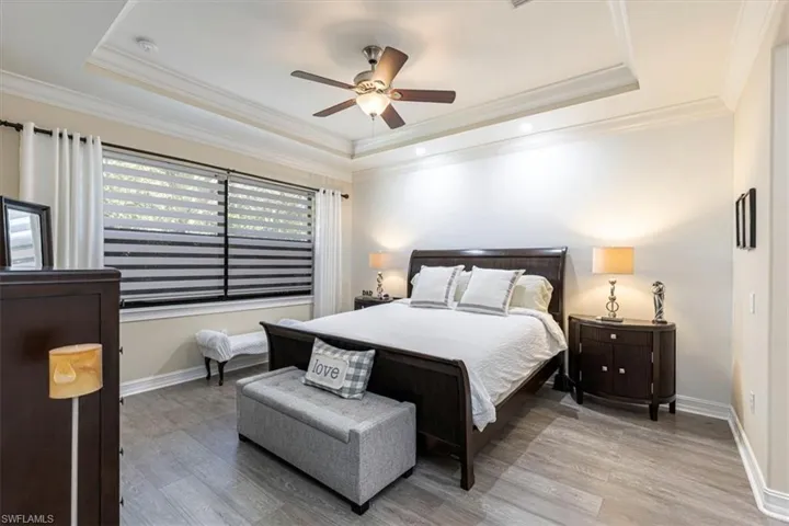 Master Bedroom featuring wood finished floors, crown molding, a raised ceiling, and a ceiling fan