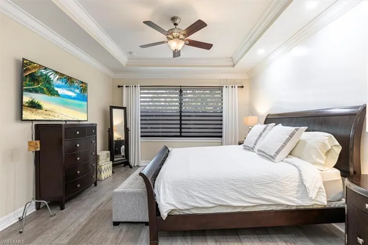 Master Bedroom with a raised ceiling, wood finished floors, ornamental molding, and a ceiling fan