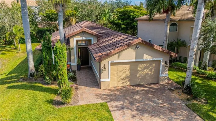 Mediterranean / spanish house with a front yard, a tile roof, stucco siding, and decorative driveway