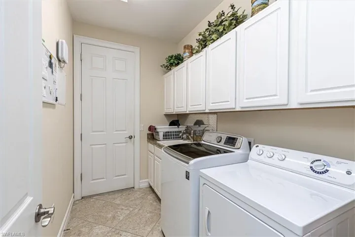 Laundry area with washing machine and dryer, cabinet space, and light tile patterned floors