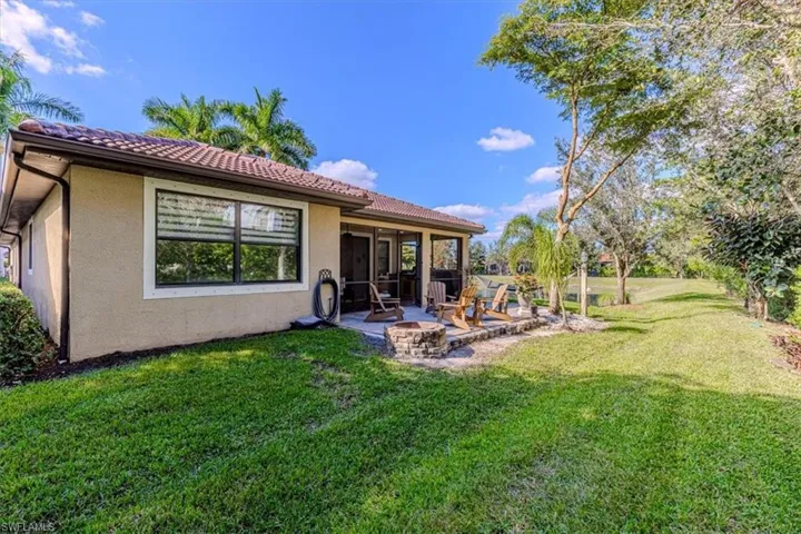 Rear view of property with stucco siding, a lawn, and a fire pit