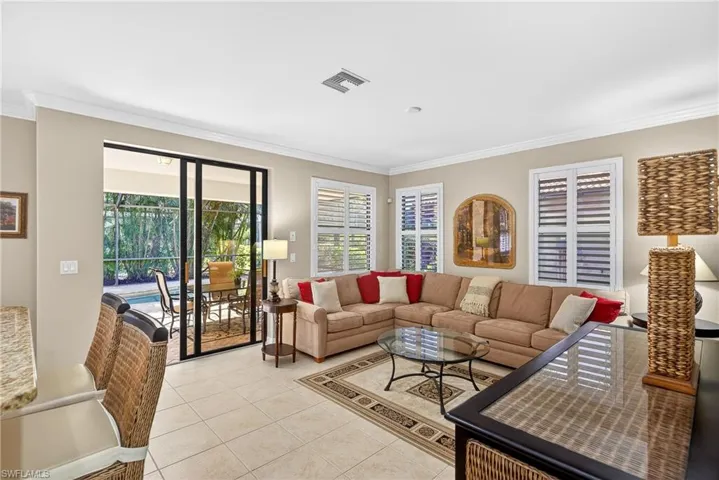 Living area with ornamental molding, tile flooring, and views of the pool