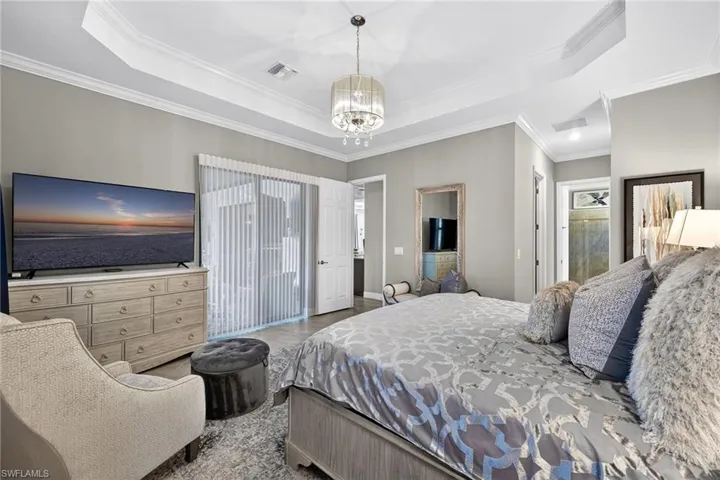 Bedroom with suspended lighting, a raised ceiling, and crown molding