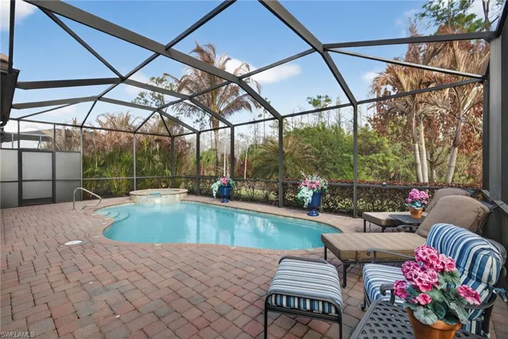 Combined pool / hot tub featuring a sunroom, a lanai, and a patio