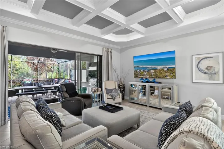 Living room with a sunroom, coffered ceiling, and ornamental molding