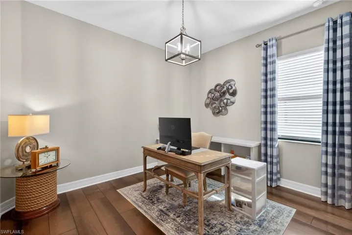 Office area featuring dark wood-type flooring and a chandelier