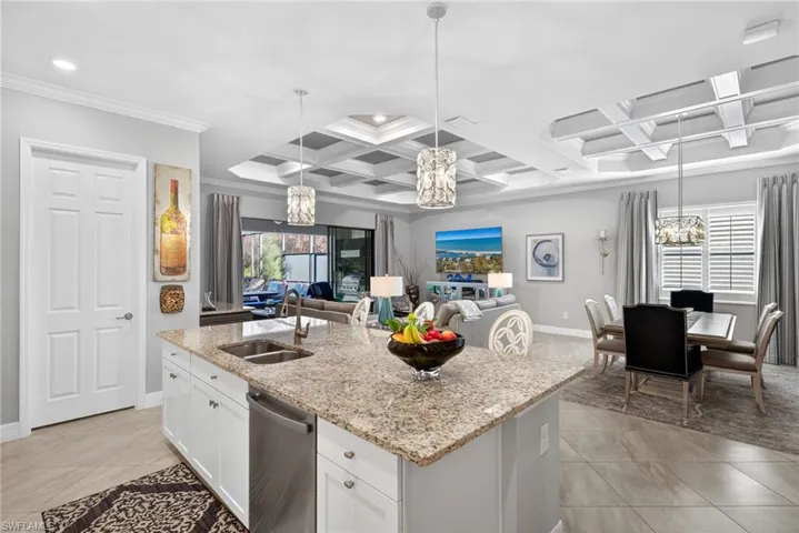 Kitchen featuring a chandelier, white cabinetry, light stone counters, stainless steel dishwasher, and coffered ceiling