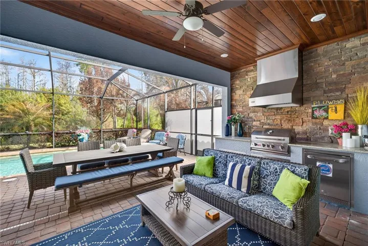 View of patio with a sunroom, an outdoor kitchen / dining area, glass enclosure, an outdoor pool, and a ceiling fan