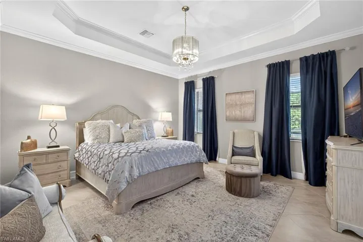 Bedroom with a chandelier, crown molding, and a raised ceiling