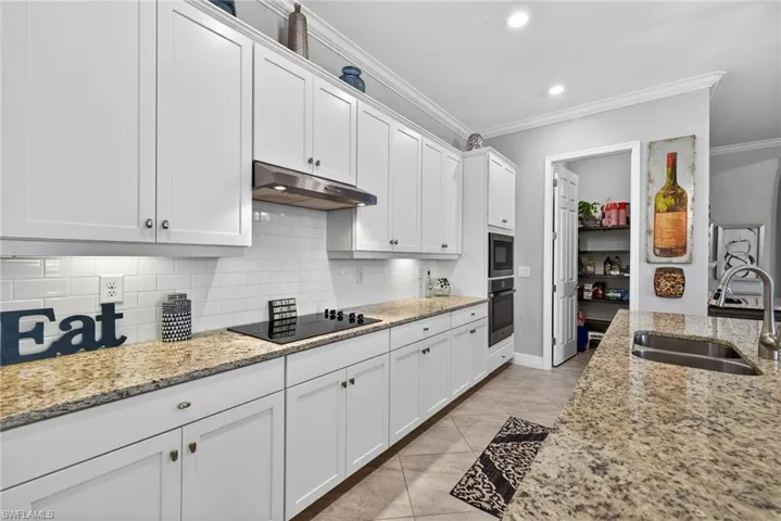Kitchen featuring ornamental molding, white cabinets, light stone counters, recessed lighting, and oven