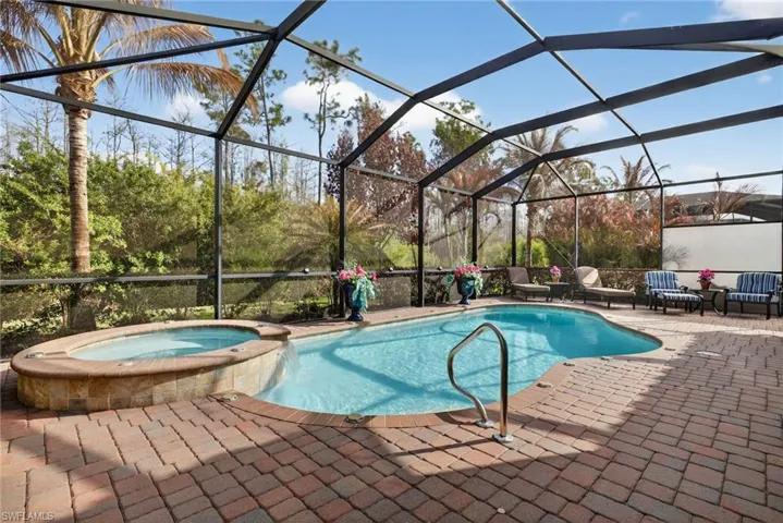 Combined pool / hot tub featuring glass enclosure, a sunroom, and a patio