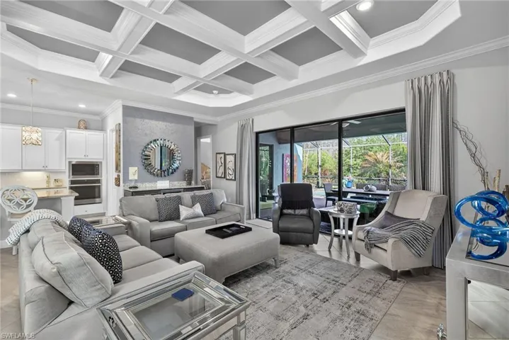 Living room featuring coffered ceiling, ornamental molding, and recessed lighting