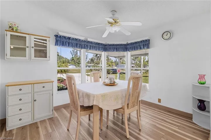 Dining room featuring a ceiling fan, a healthy amount of sunlight, a textured ceiling, and light wood finished floors